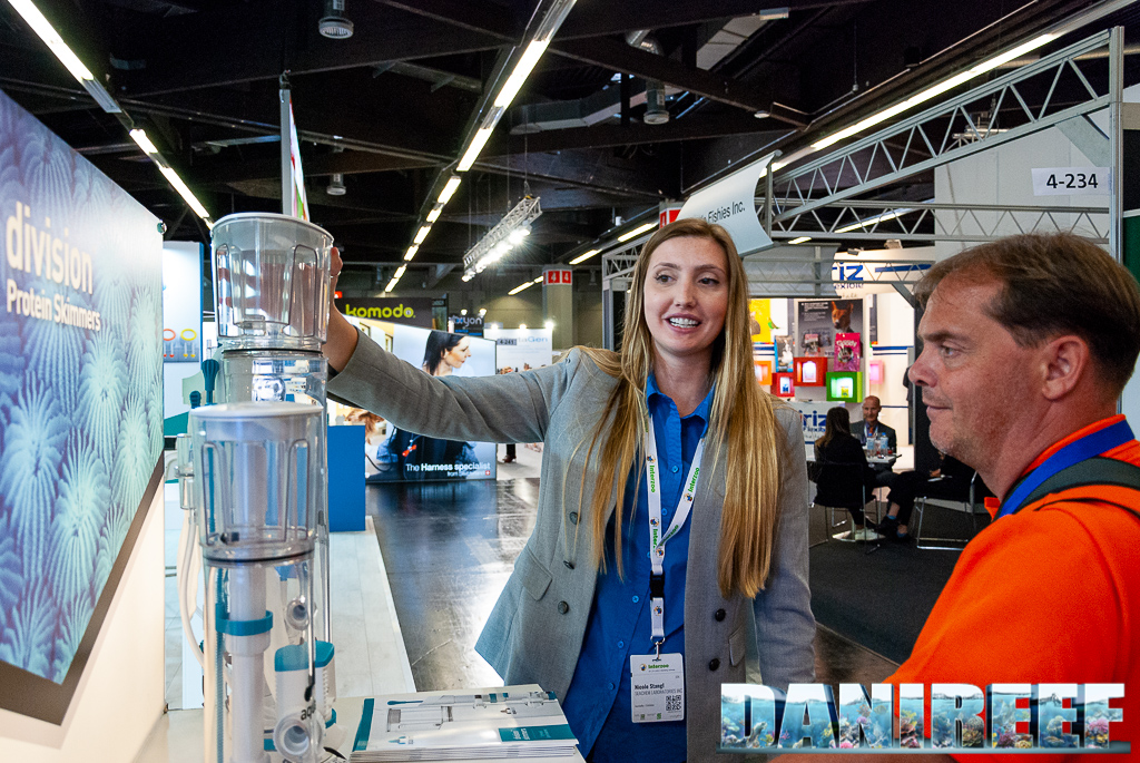 Nicole Stangl che afferra il bicchiere dei nuovi schiumatoi AquaVitro Division allo stand Seachem durante Interzoo 2022 sotto lo sguardo incuriosito di DaniReef