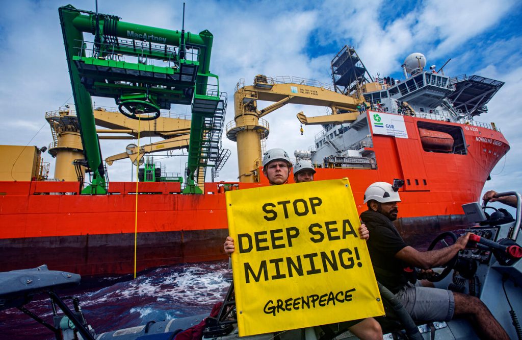 Greenpeace International activists from the Rainbow Warrior attach a flag reading 'Stop Deep Sea Mining'' to the cable holding the prototype robot, Patania II. In an action to disturb a new deep sea mining impact test carried out by the company Global Sea Mineral Resources (GSR) after a recent major failure that resulted in a 25-tonne mining robot left stuck on the Pacific Ocean seafloor for days. An activist also holds a banner reading 'Stop Deep Sea Mining'.
The Greenpeace ship is in the Clarion Clipperton Zone in the Pacific to bear witness to the deep sea mining industry. Part of the ongoing 'Protect the Oceans' campaign.